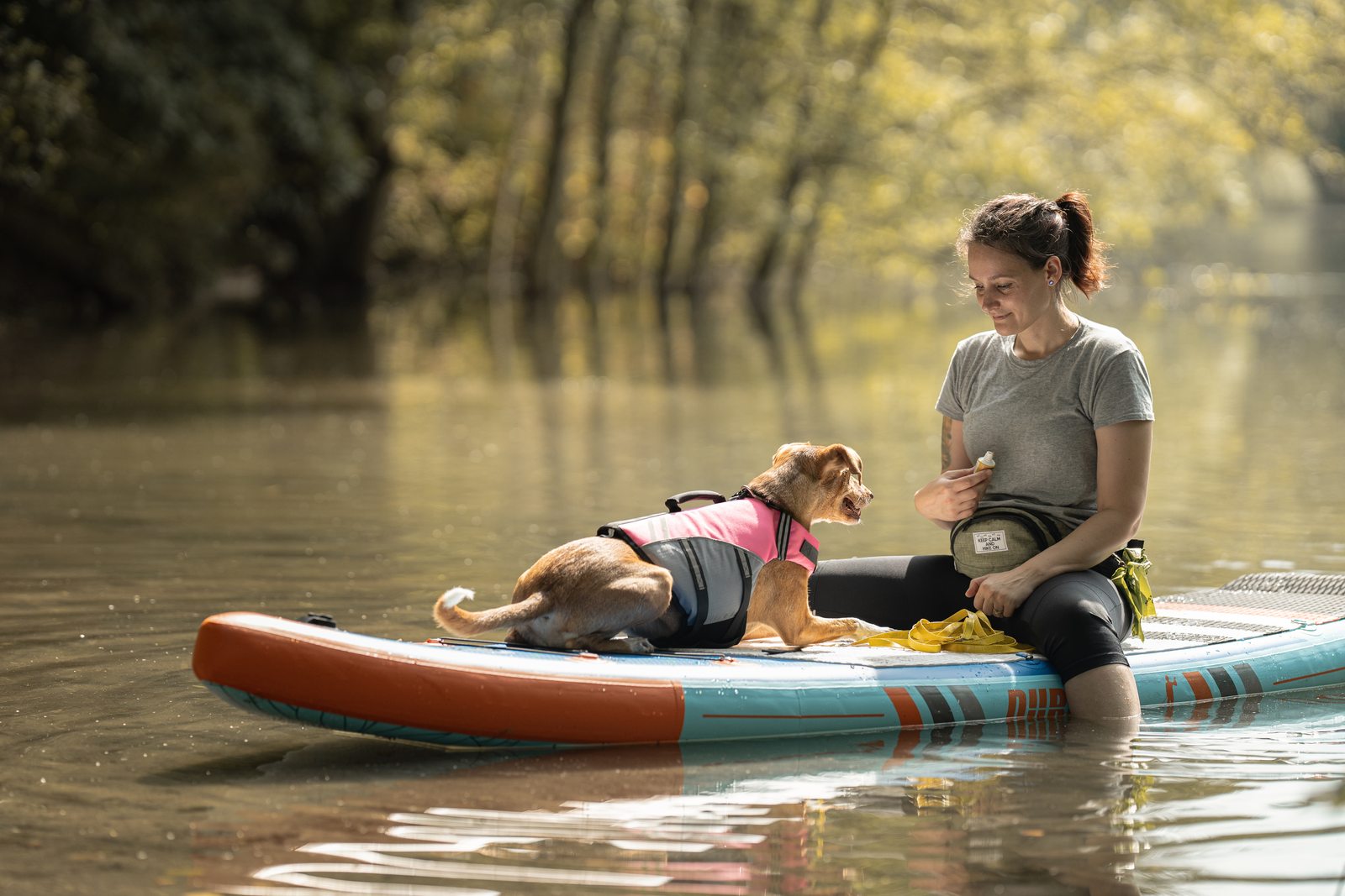 Frau mit Hund auf dem SUP-Board am Wasser