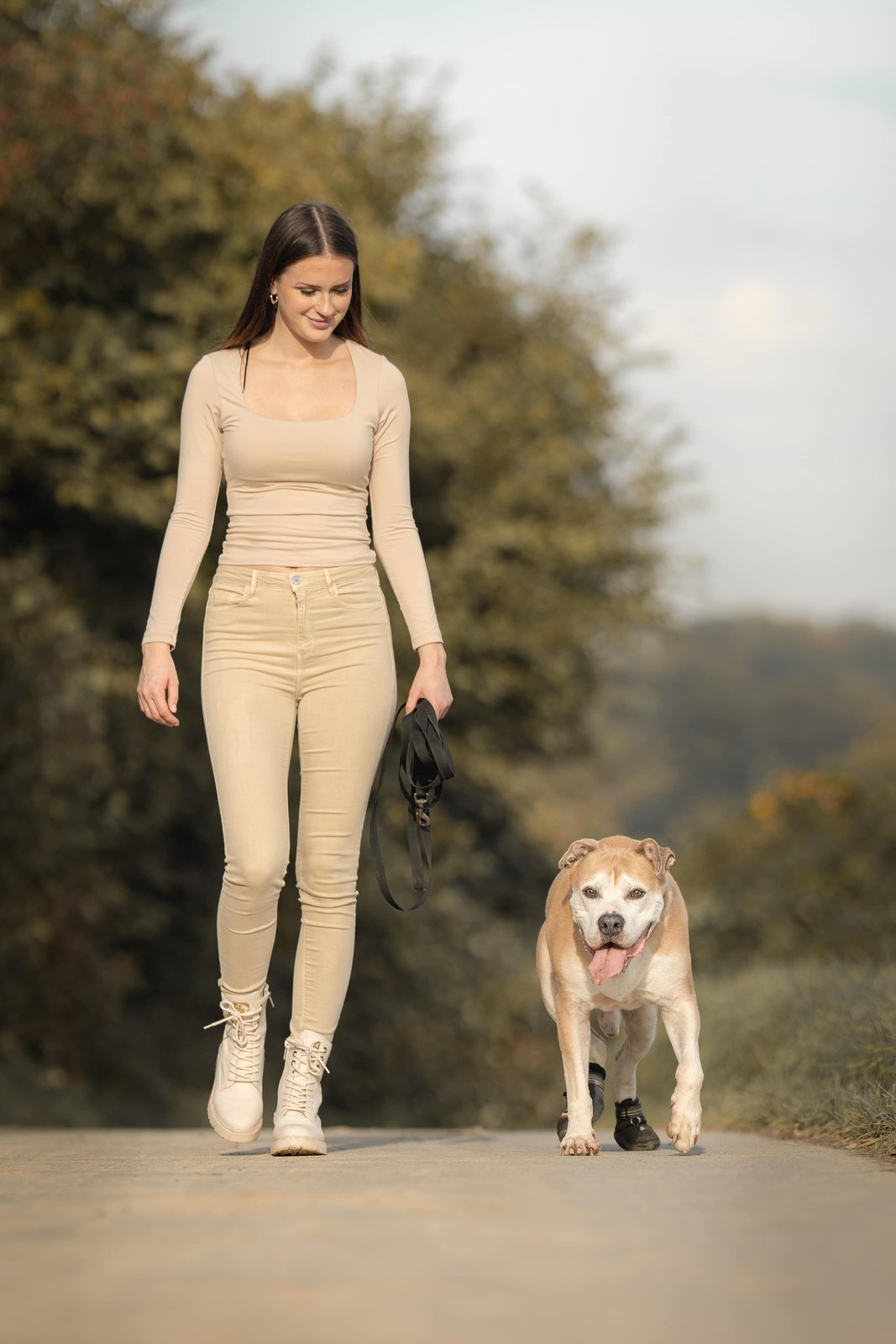 Frau spaziert entspannt mit ihrem Hund über den Weg