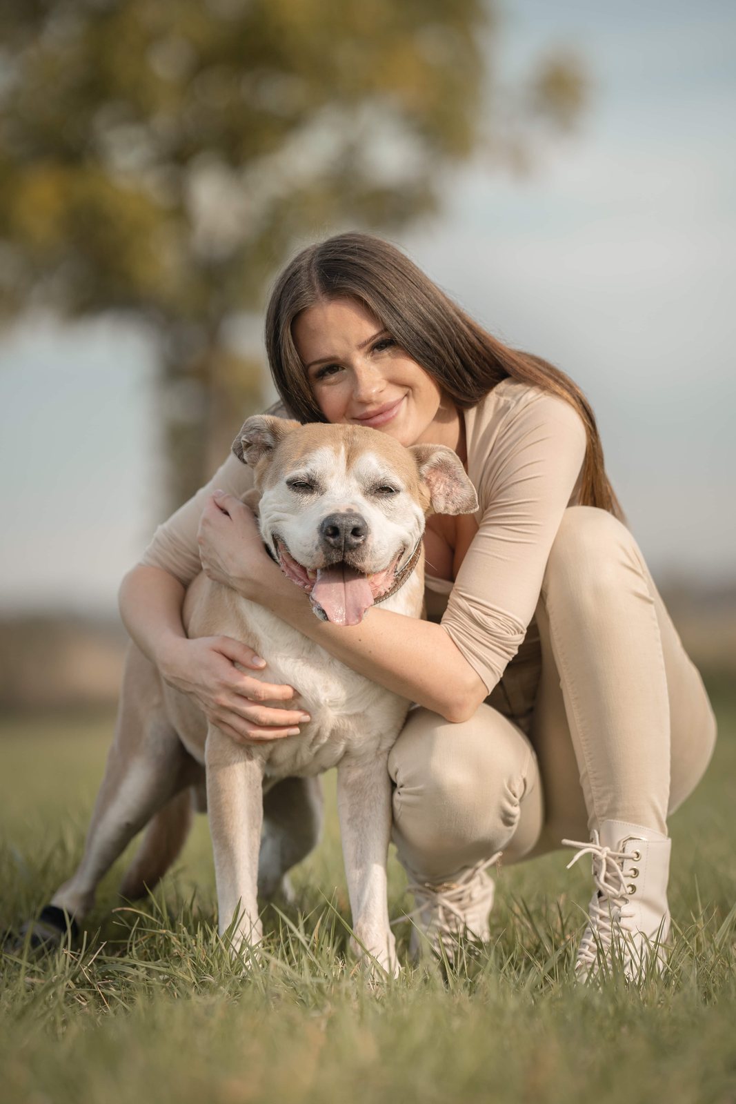 Frau umarmt ihren lächelnden Hund auf der Wiese